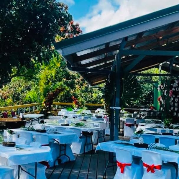 Tables nappées de bleu et chaises habillées de rouge pour une réception en plein air