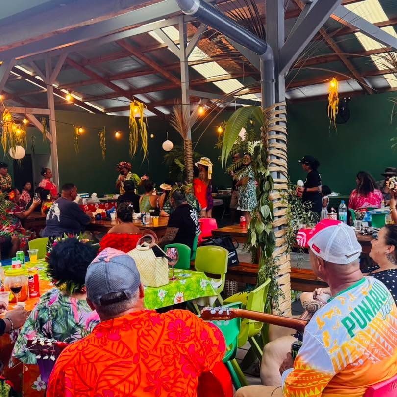 Grand repas convivial sous le fare avec guirlandes et musiciens